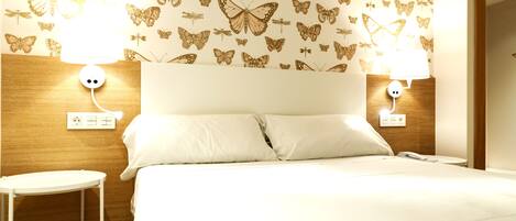 Une chambre d’hôtel avec un lit, deux tables de chevet et un papier peint orné de motifs de papillons.