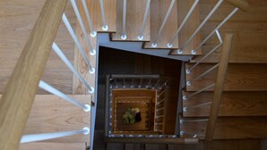 Una escalera de madera con barandilla metálica y un pequeño espacio cerrado en la parte superior.