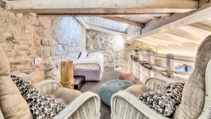 A cozy room with a bed, wicker chairs, and a stone wall. - Giglio Apartments by Mmega (Florence)
