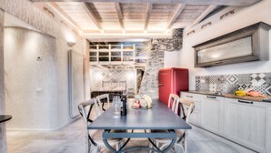 A dining area with a table set for two, a red refrigerator, and a kitchen area with patterned tiles. - Giglio Apartments by Mmega (Florence)