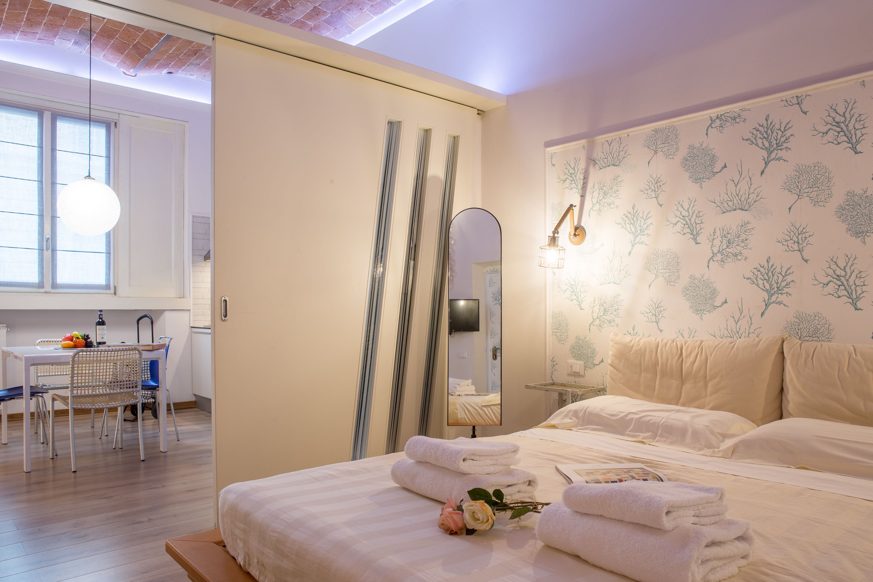 Een hotelkamer met een bed, nachtkastje en een bureau met stoel.