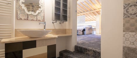 A bathroom with a large mirror, a white sink, and a patterned floor.