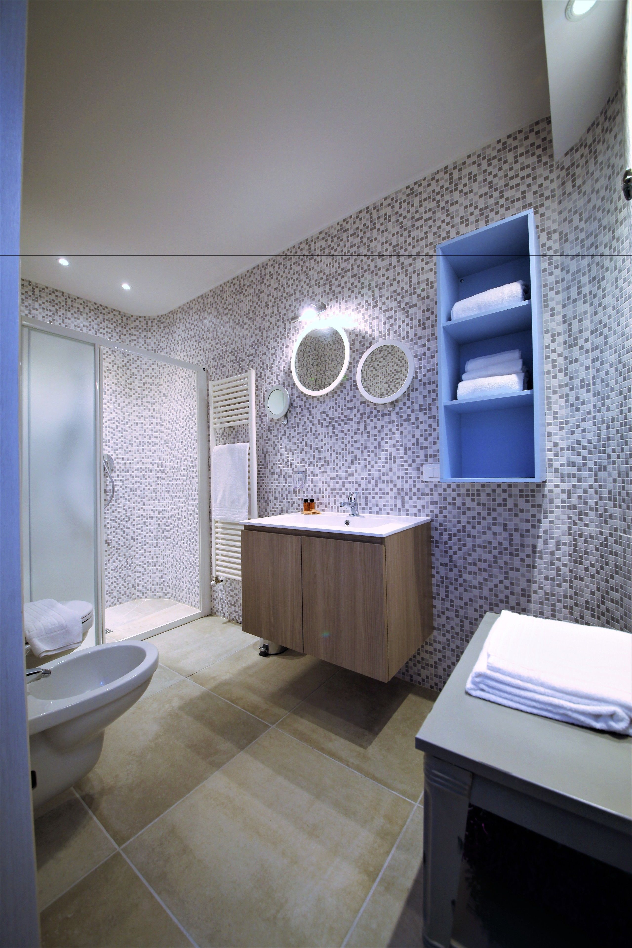 Ein Badezimmer mit Dusche, Toilette, Waschbecken und einem blauen Handtuchhalter.