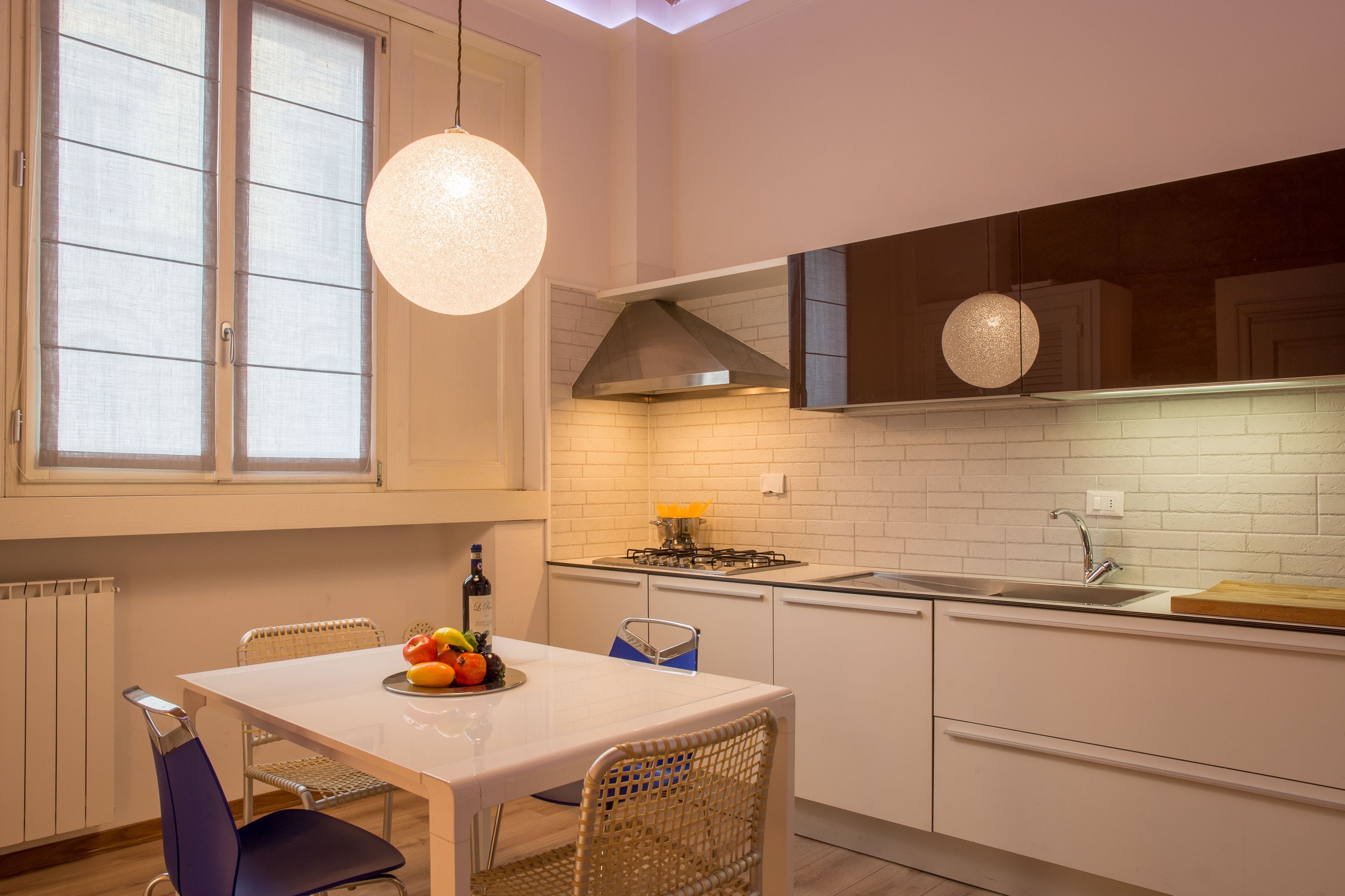 A modern kitchen with white cabinets, a white countertop, a gas stove, and a hanging light fixture.