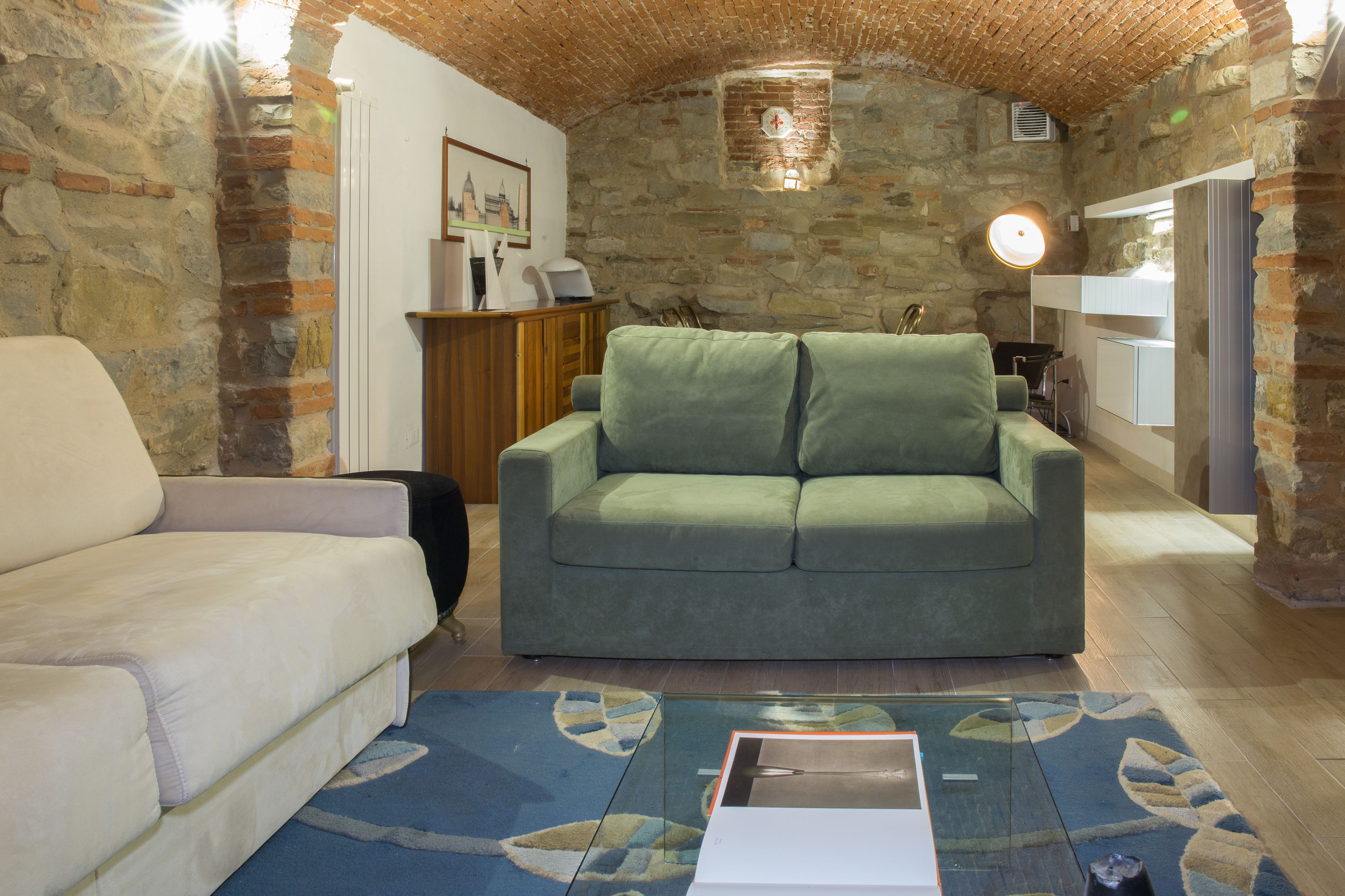 Un salon chaleureux avec un canapé vert, un canapé blanc et un tapis bleu à motifs.