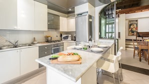 Eine moderne Küche mit weißen Schränken, einer Marmorarbeitsplatte und einem Essbereich mit Holztisch und -stühlen.