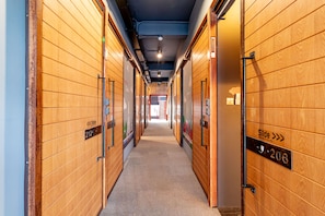 A corridor with wooden panel walls, numbered doors, and a carpeted floor. - Cloud on Saladaeng Silom Hostel Bangkok (Bangkok)