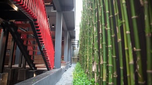 A corridor with a red staircase and bamboo plants. - Cloud on Saladaeng Silom Hostel Bangkok (Bangkok)