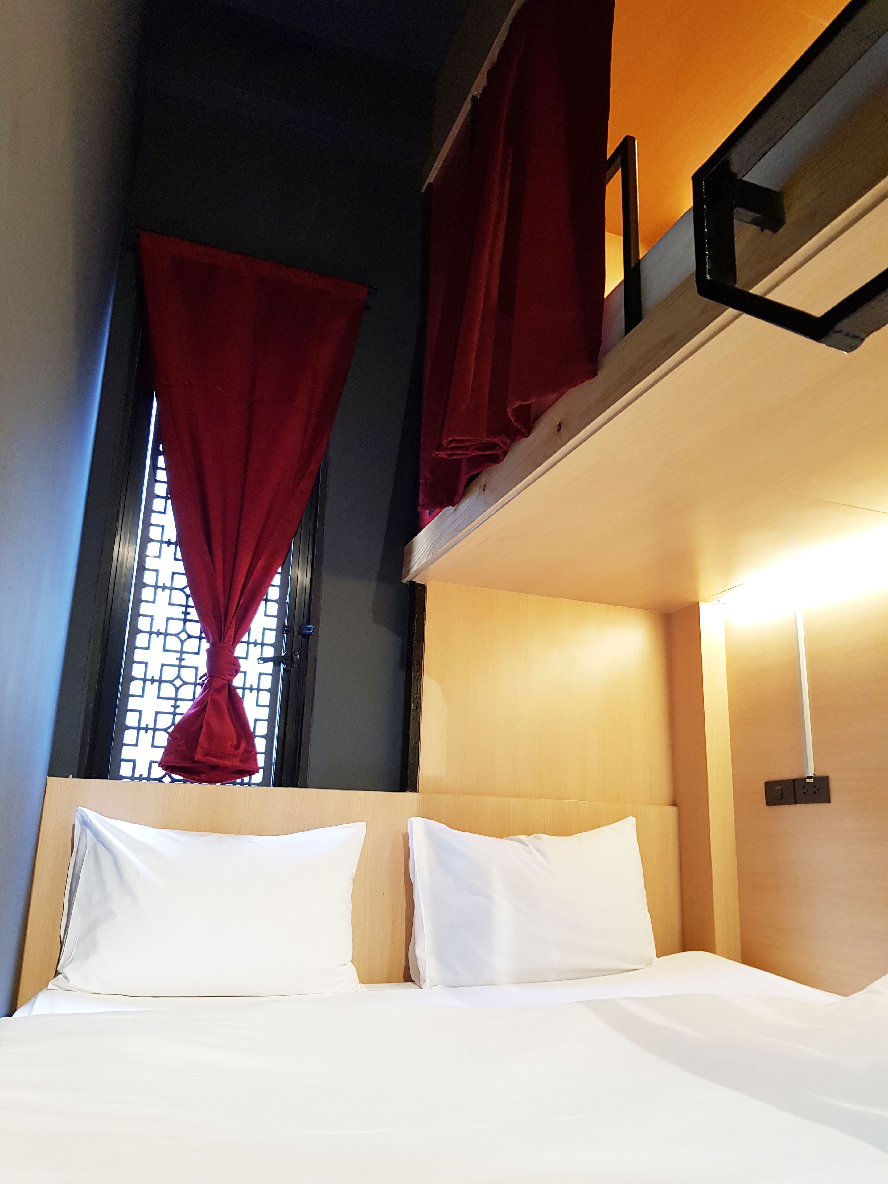 A bunk bed room with a window, red curtains, and a headboard.