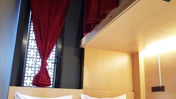 A bunk bed room with a window, red curtains, and a headboard.