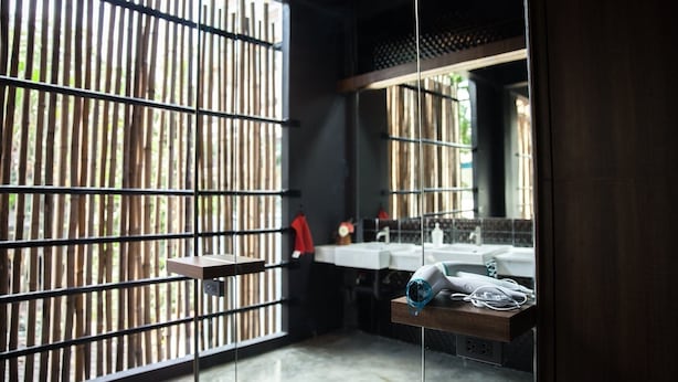 A bathroom with a bamboo partition, a sink, and a hairdryer on a shelf. - Cloud on Saladaeng Silom Hostel Bangkok (Bangkok)