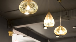 A long bar area with a wooden counter, hanging pendant lights, and stools. - Cloud on Saladaeng Silom Hostel Bangkok (Bangkok)