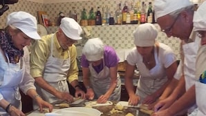 A group of people in a kitchen preparing food, with a large bowl and dough on the counter. - Agriturismo Natura e Salute (San Gimignano)