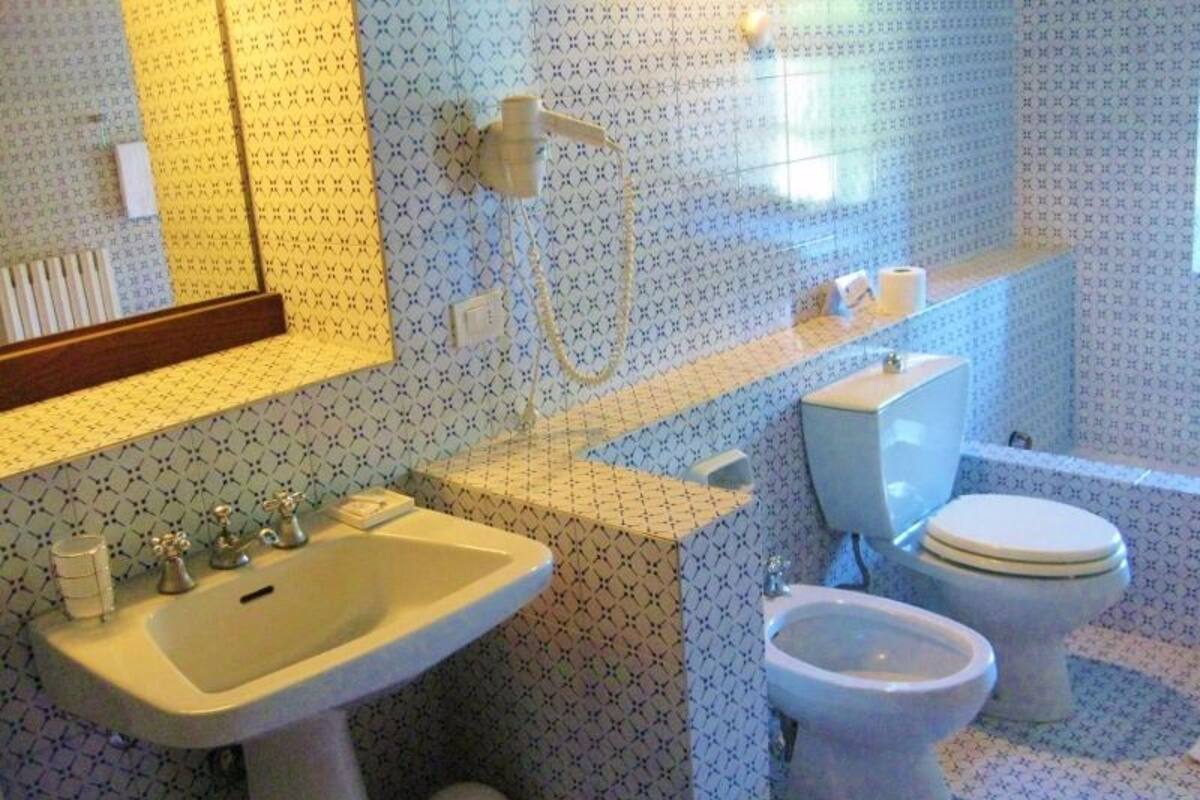 A bathroom with a sink, toilet, bidet, and a mirror above the sink.