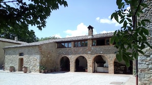 A stone building with a courtyard, featuring arched doorways and a tiled roof. - Agriturismo Natura e Salute (San Gimignano)