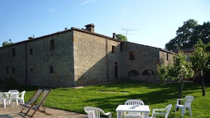 A stone building with a pool, outdoor seating, and a well-maintained lawn. - Agriturismo Natura e Salute (San Gimignano)