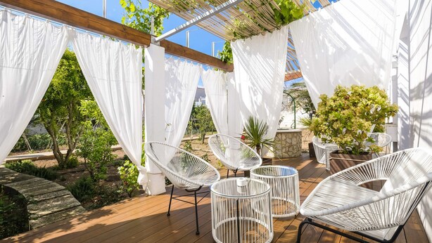 An outdoor patio with white canopies, wicker chairs, and potted plants. - Hotel Abril 37 (Ciutadella de Menorca)