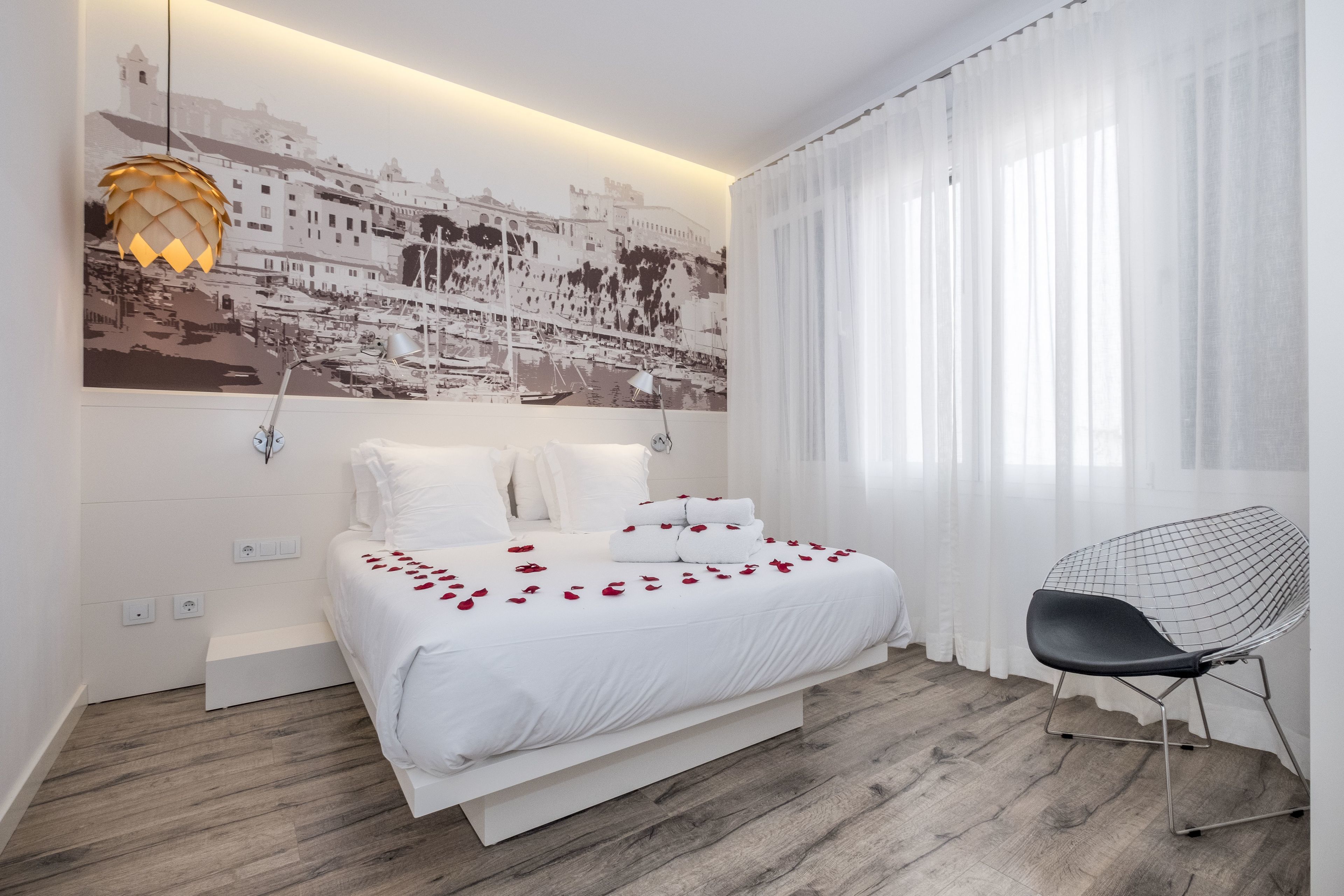 A modern bedroom with a bed, a chair, and a wall-mounted lamp.