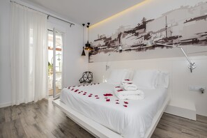 Een moderne slaapkamer met een groot bed, witte beddengoed en rozenblaadjes op het bed.