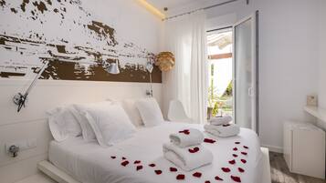 Une chambre d’hôtel moderne avec un grand lit, du linge de lit blanc et une vue sur l’extérieur grâce à une porte vitrée.
