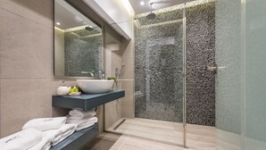 A modern bathroom with a glass shower enclosure, a large mirror, and a built-in sink with a countertop. - Venus Resort (Zakynthos)