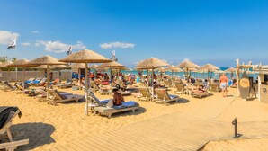 A beach with sun loungers, umbrellas, and a wooden boardwalk. - Venus Resort (Zakynthos)