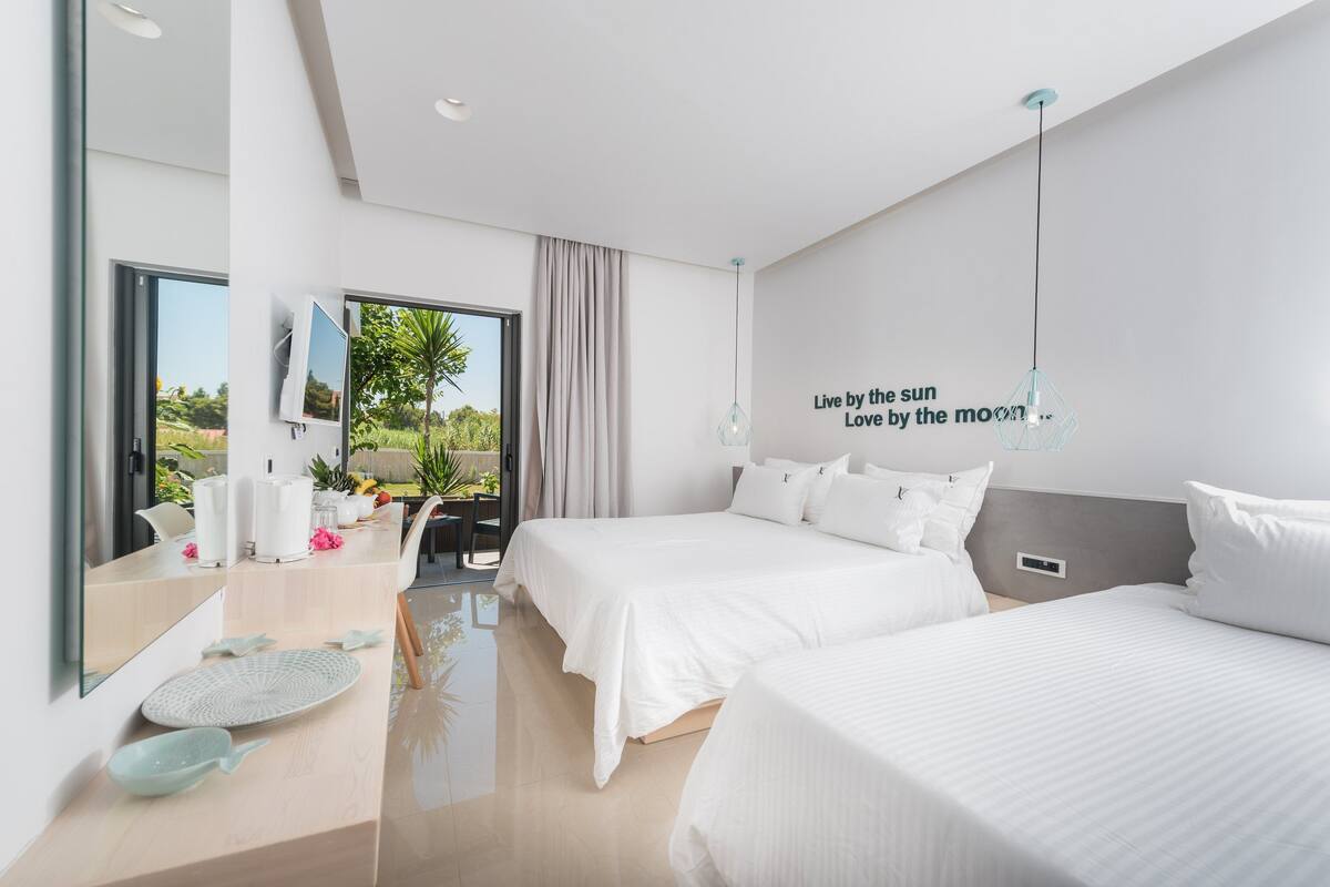 A modern hotel room with a large bed, a smaller bed, a desk, and a view of the outdoors.
