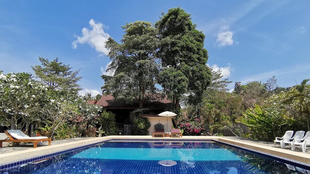 A clear blue swimming pool with lounge chairs and a pavilion in the background. - Lanta Whiterock Resort (Ko Lanta)