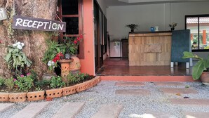 A reception area with a wooden sign, potted plants, and a tiled entrance. - Lanta Whiterock Resort (Ko Lanta)