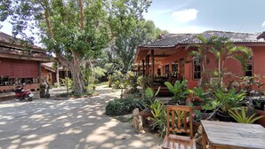 A courtyard with a traditional building, a wooden chair, and various potted plants. - Lanta Whiterock Resort (Ko Lanta)