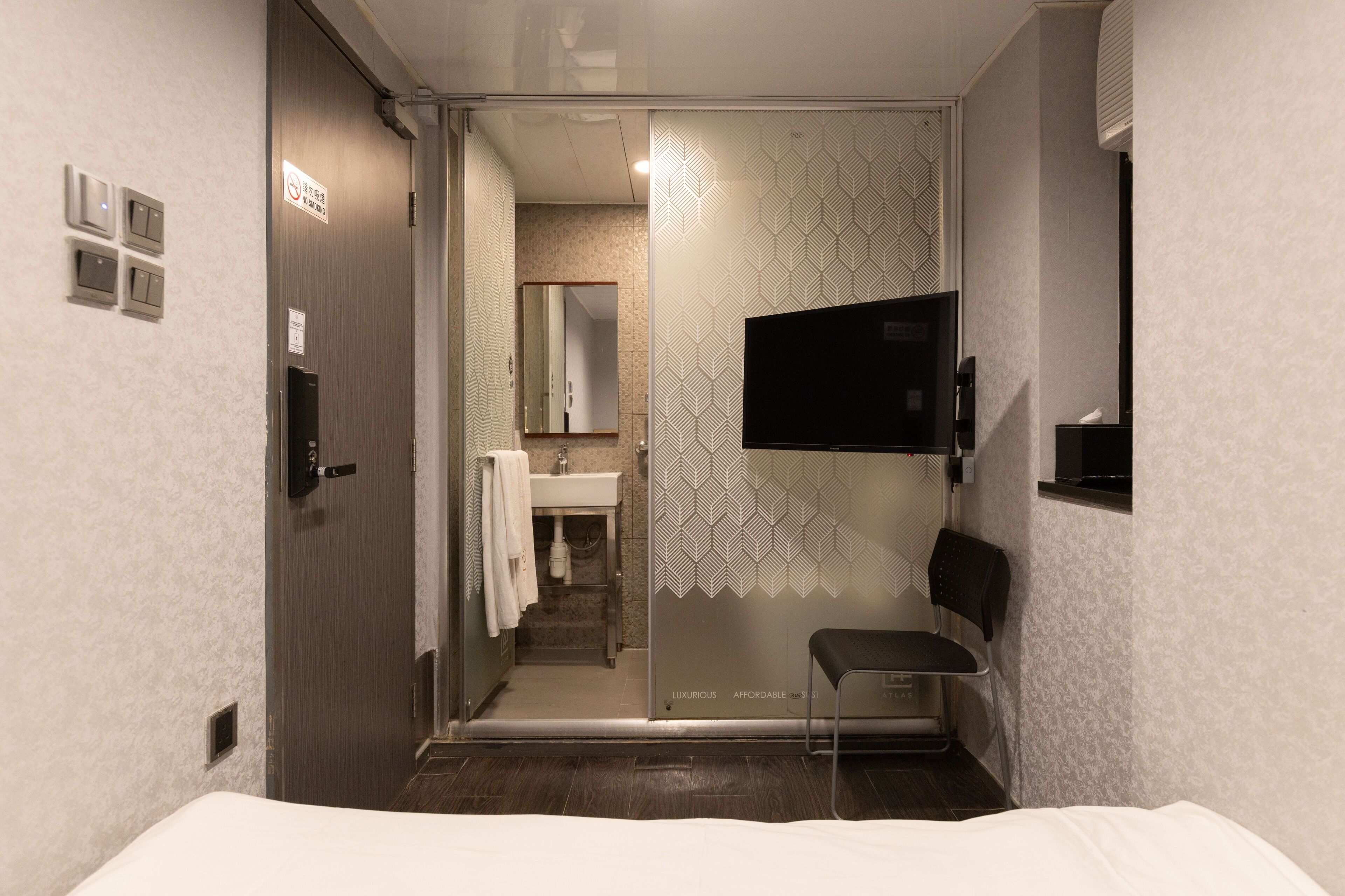 A modern bathroom with a glass partition, a sink, a mirror, and a toilet.