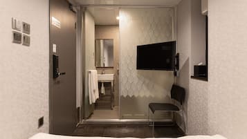 A modern bathroom with a glass partition, a sink, a mirror, and a toilet.