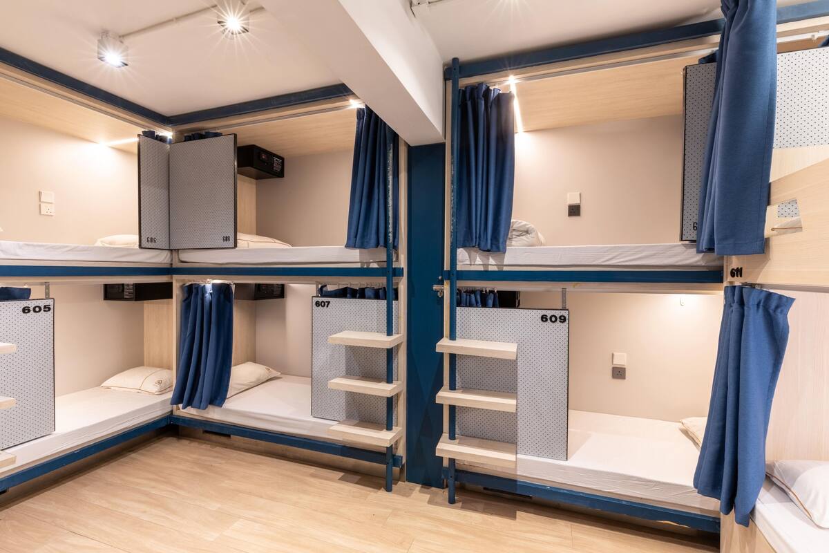 A hotel room with bunk beds, each bed labeled with a number, and a wardrobe with a mirror.