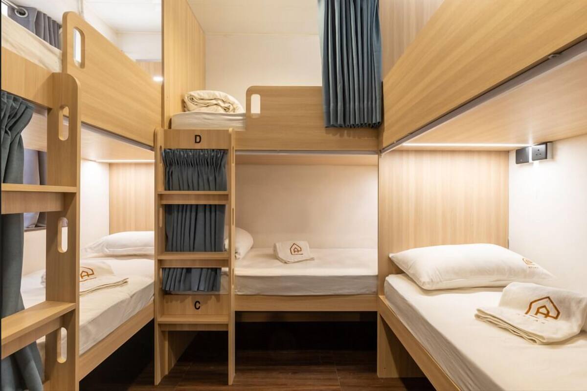 A bunk bed room with a ladder, a desk, and a window with curtains.