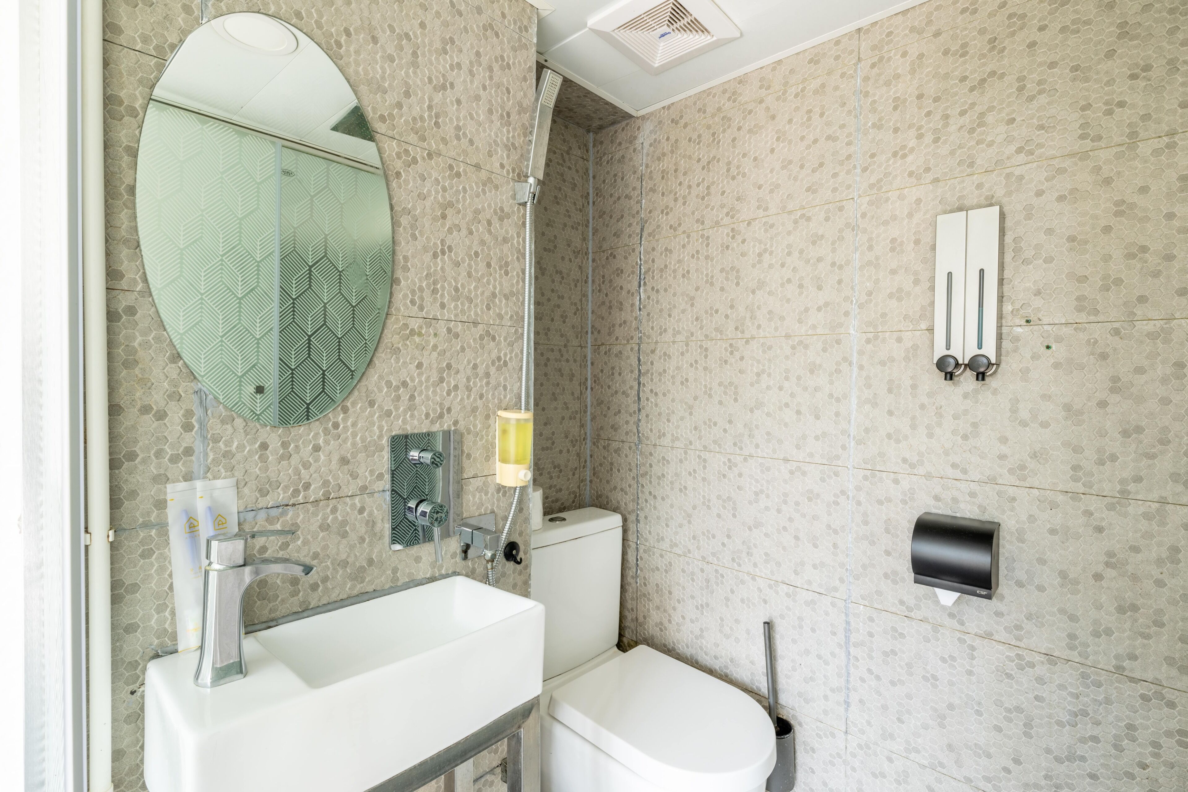A modern bathroom with a large mirror, a sink, a toilet, and a shower.