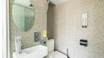 A modern bathroom with a large mirror, a sink, a toilet, and a shower.