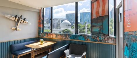Un coin salon avec une table et des chaises, un luminaire décoratif et une fresque murale.