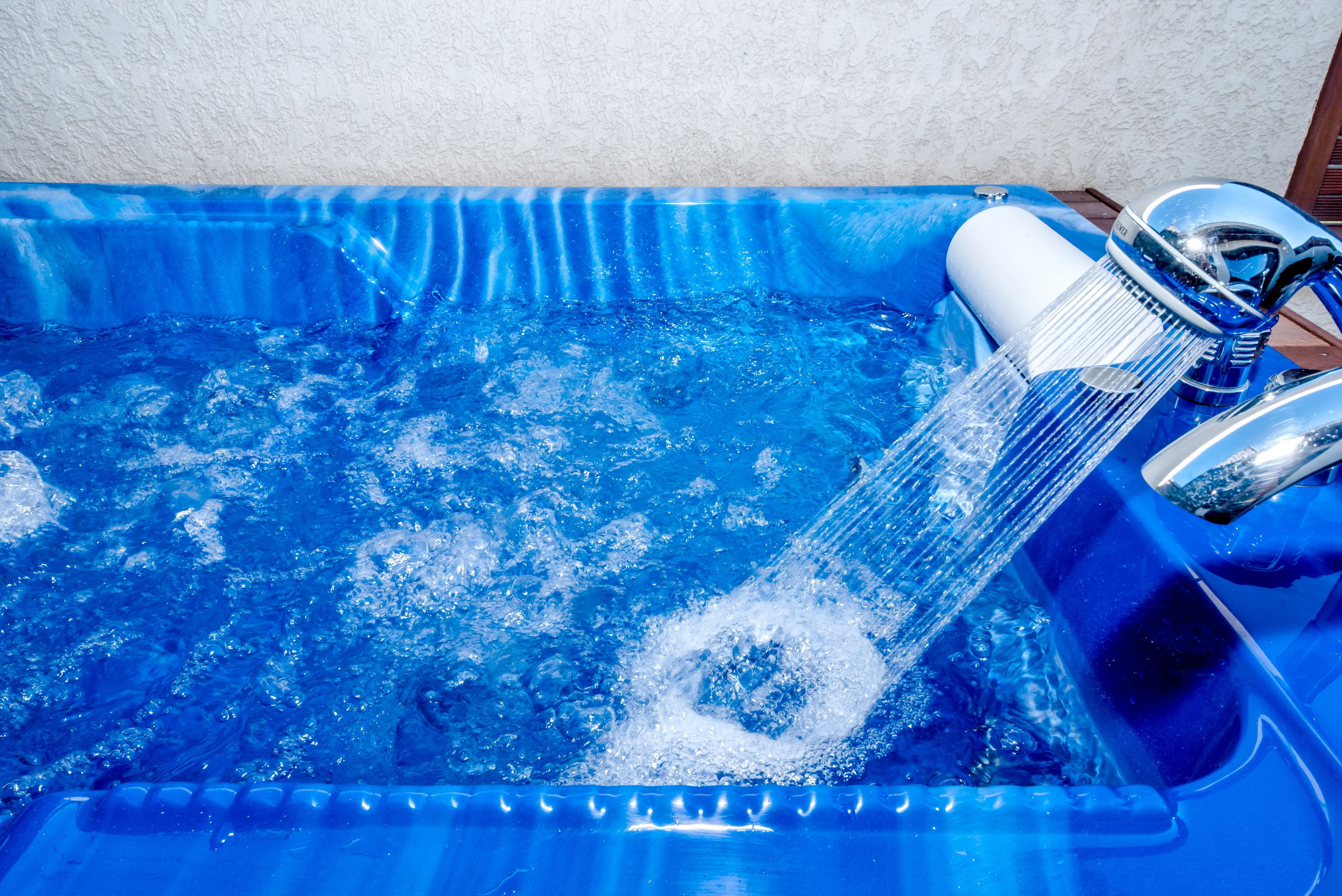 A blue pool with clear water and a faucet.