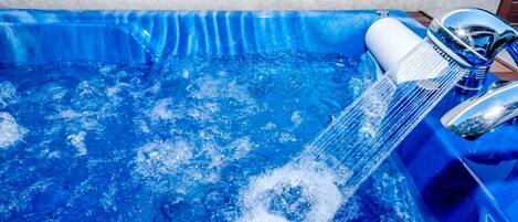 A blue pool with clear water and a faucet.