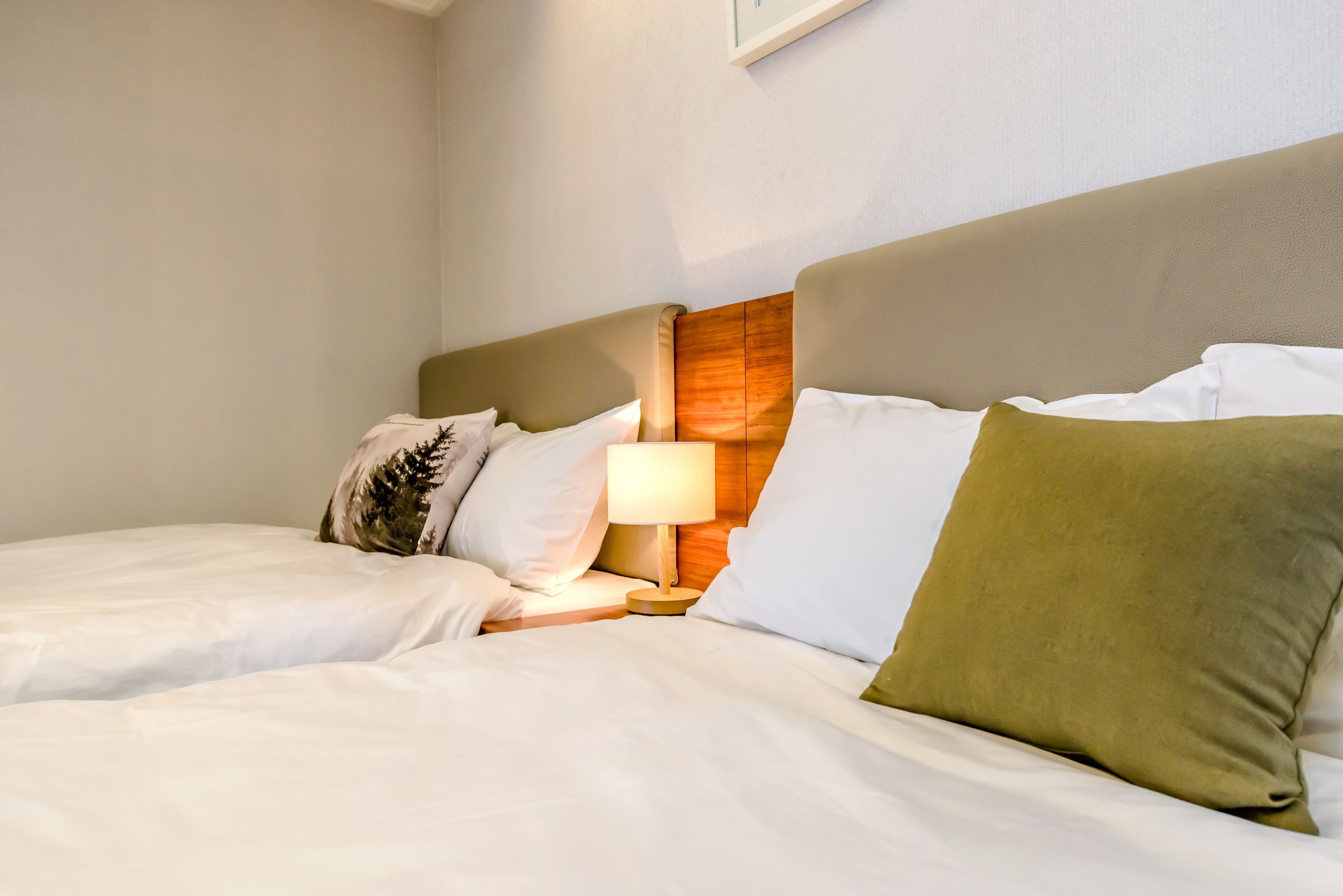 Quarto de hotel com cama, mesa de cabeceira e abajur.