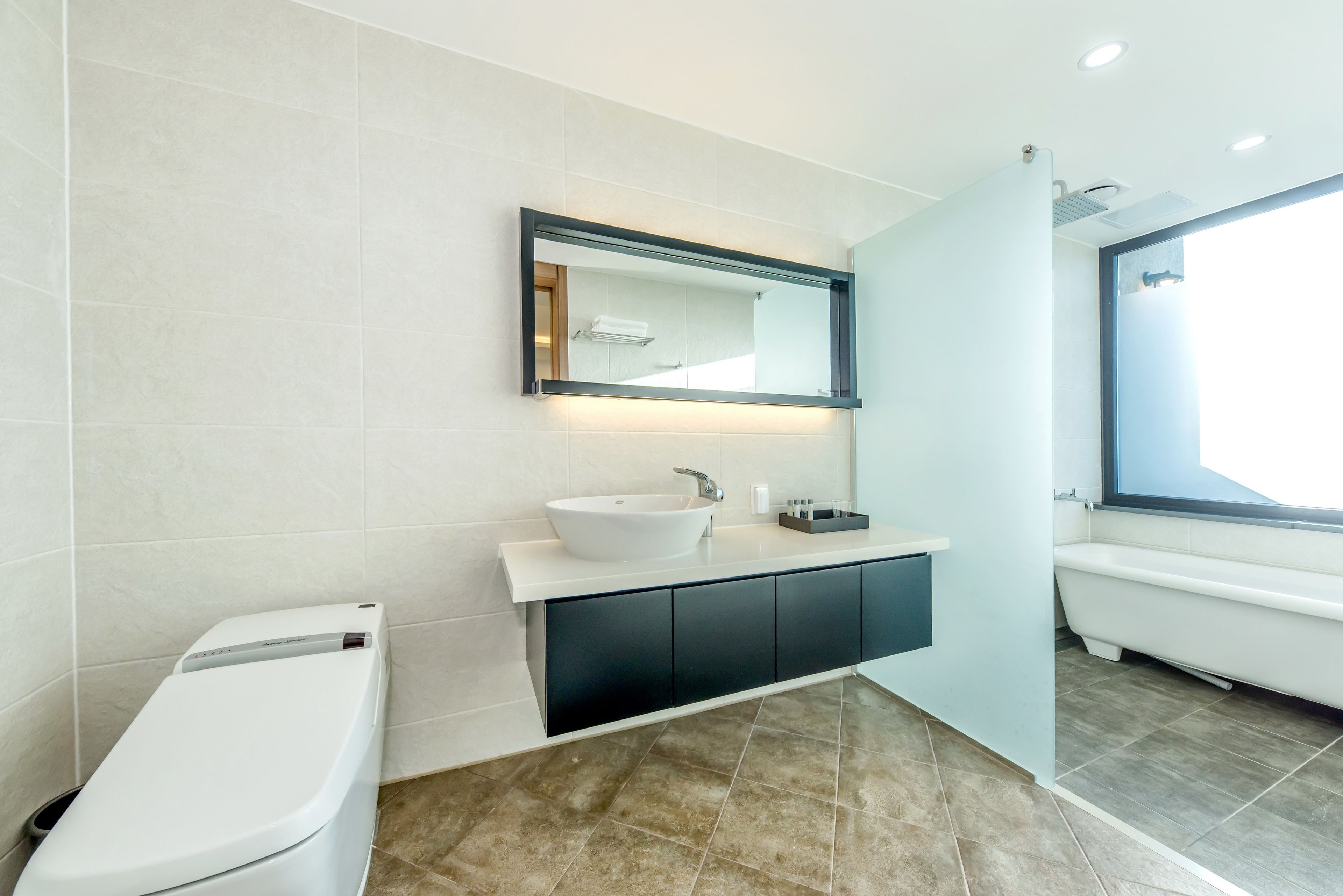 Une salle de bain moderne avec un lavabo blanc, des meubles noirs et un grand miroir.