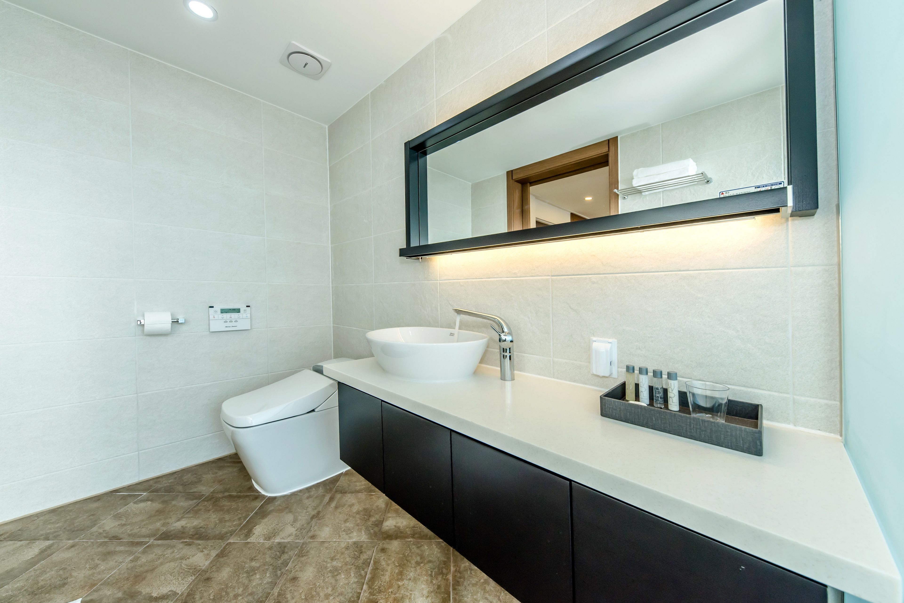 A modern bathroom with a white sink, black cabinets, and a large mirror.