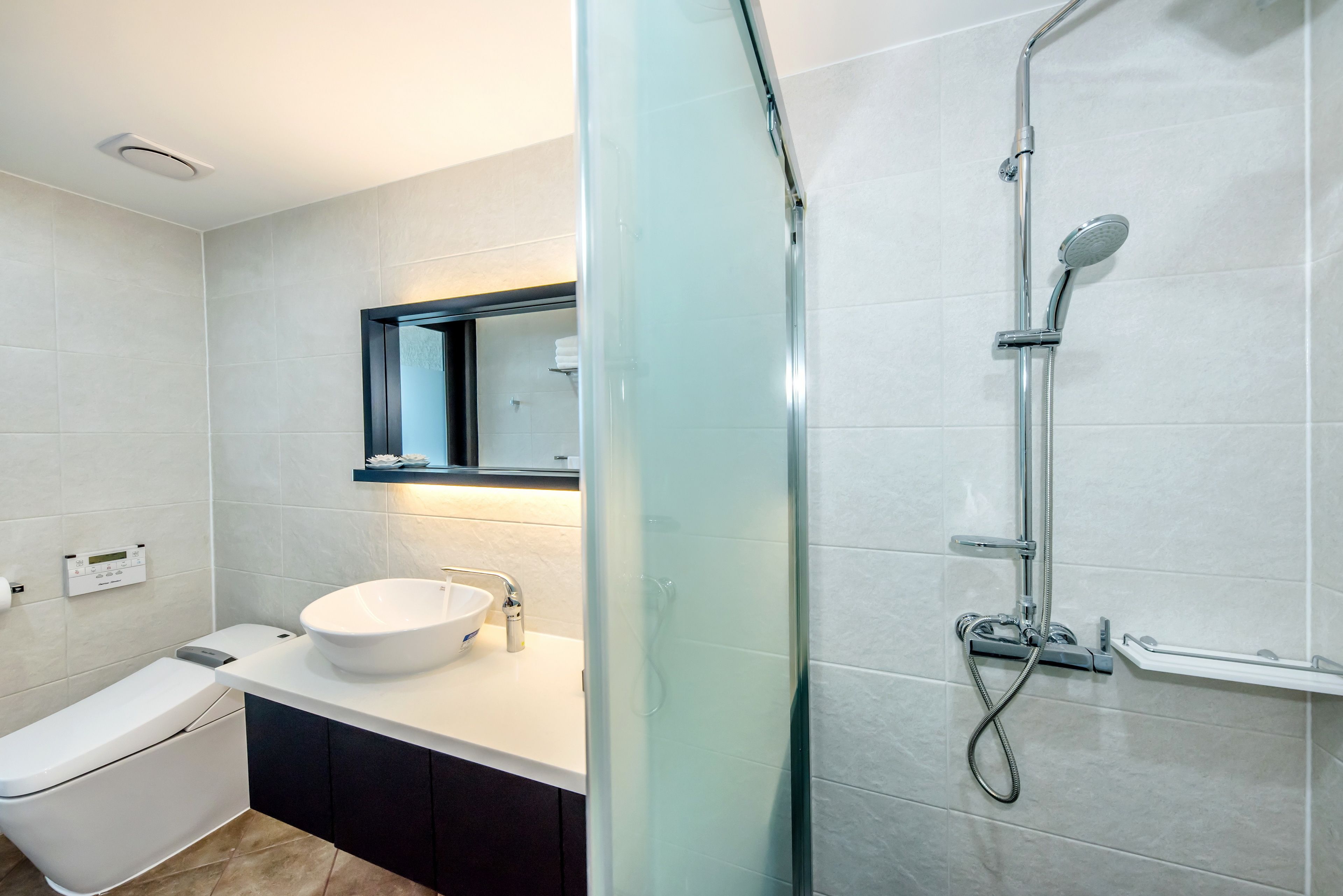 Un baño moderno con ducha envuelta en vidrio, un lavamanos blanco y un inodoro.