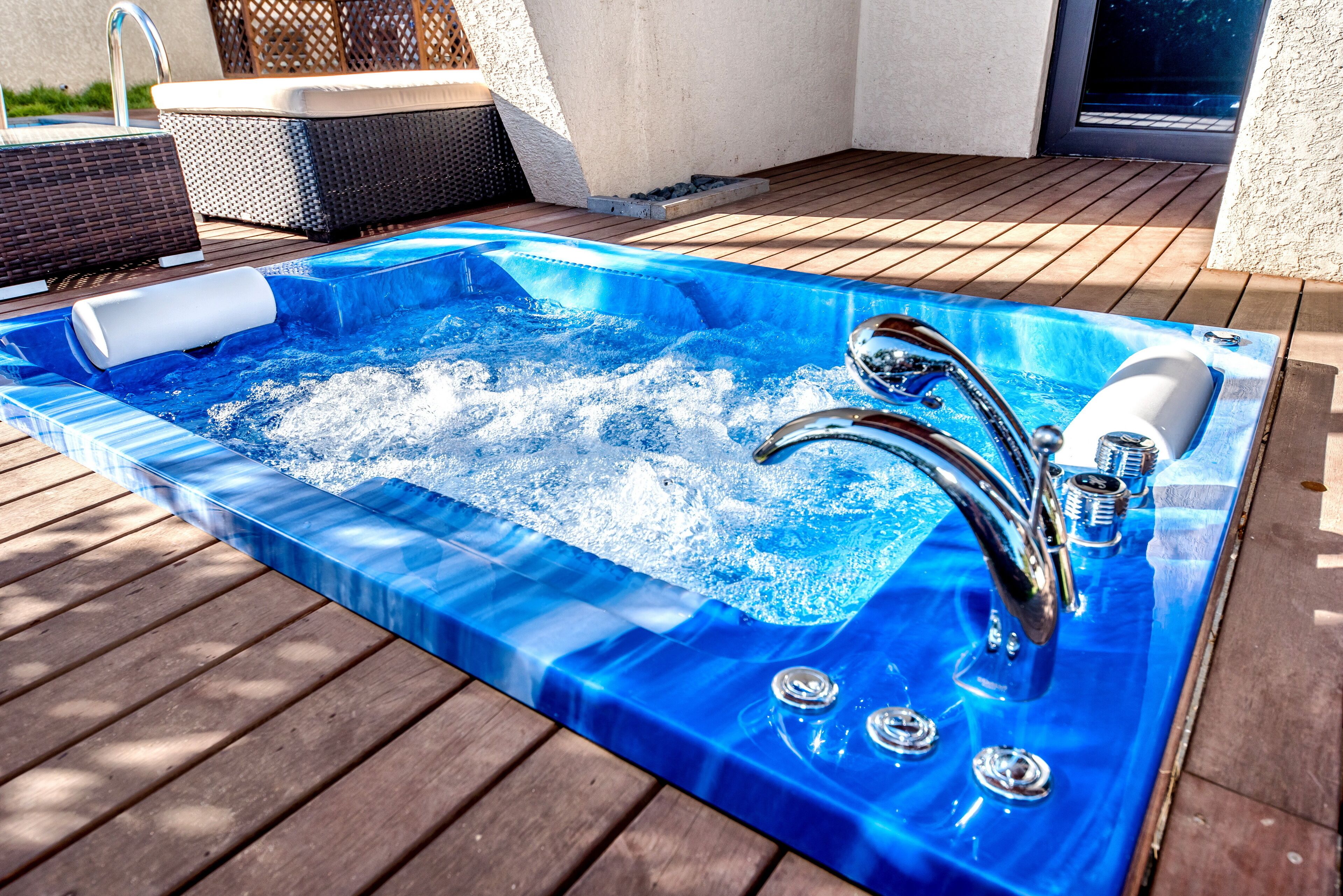 Een hottub op een houten terras, voorzien van een ingebouwde kraan en bedieningselementen.
