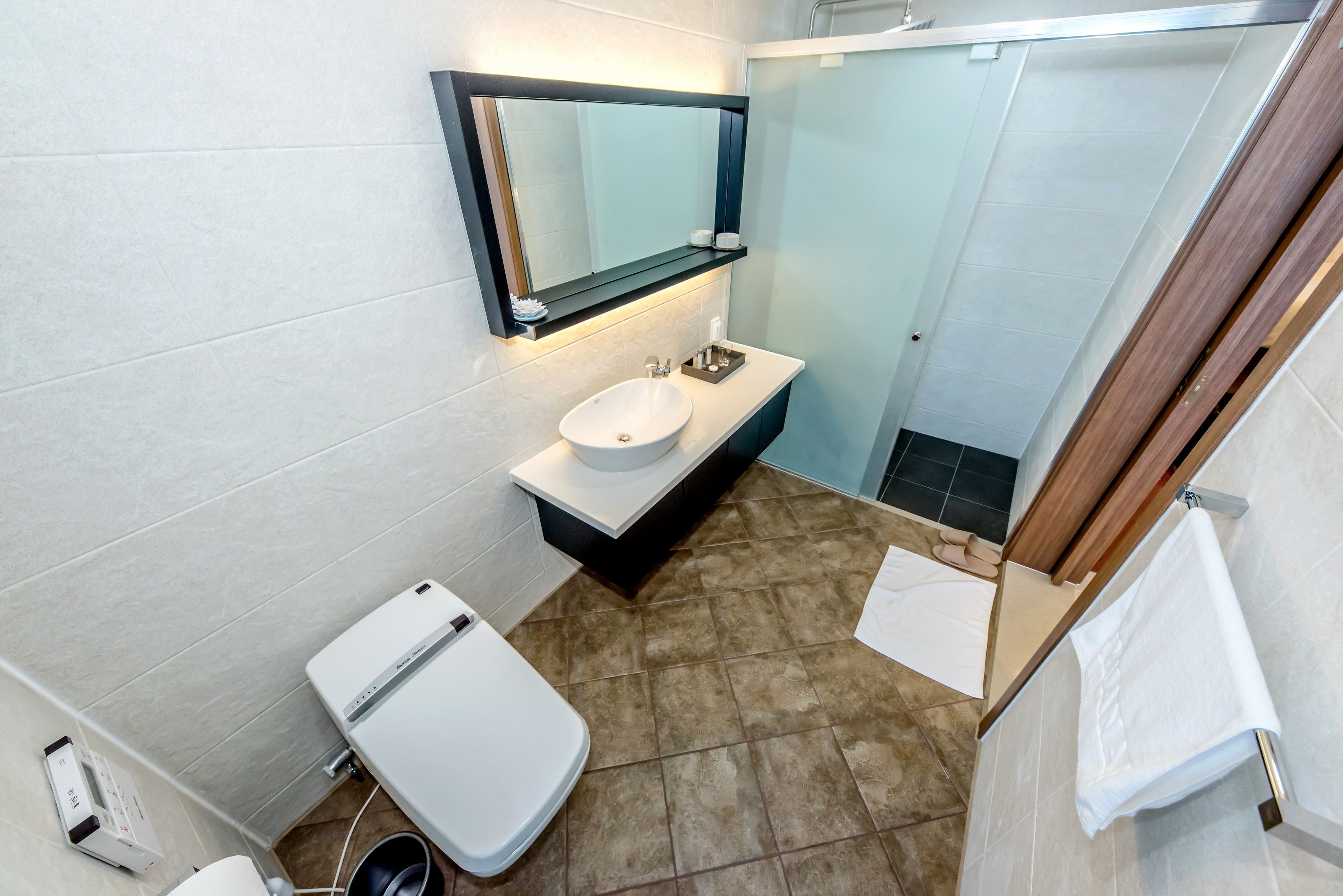 A modern bathroom with a white sink, a mirror, and a toilet.