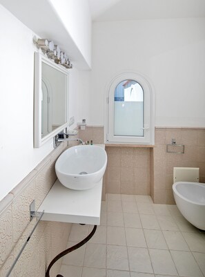 A bathroom with a large white sink, a mirror, and a window. - Casa Gaia (Capri)
