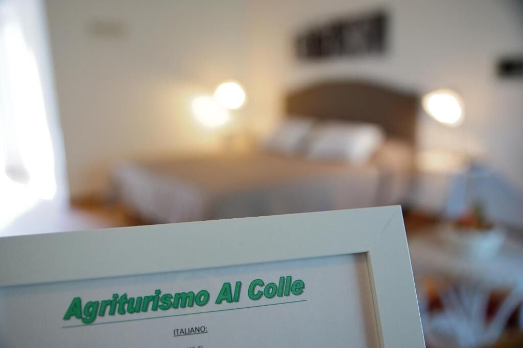 Placa emoldurada com o texto 'Agriturismo Al Colle' em um quarto de hotel.