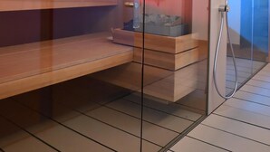 A modern sauna with glass walls, wooden benches, and a visible shower area. - Agriturismo al Colle (Bertinoro)