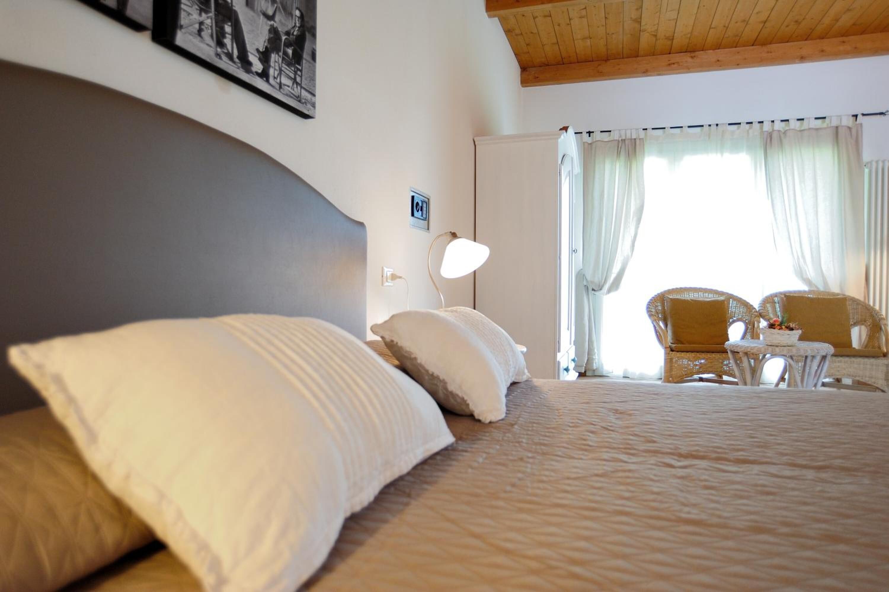 A bedroom with a large bed, a bedside lamp, a chair, and a small table.