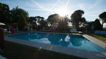 A swimming pool with a clear sky and trees in the background.